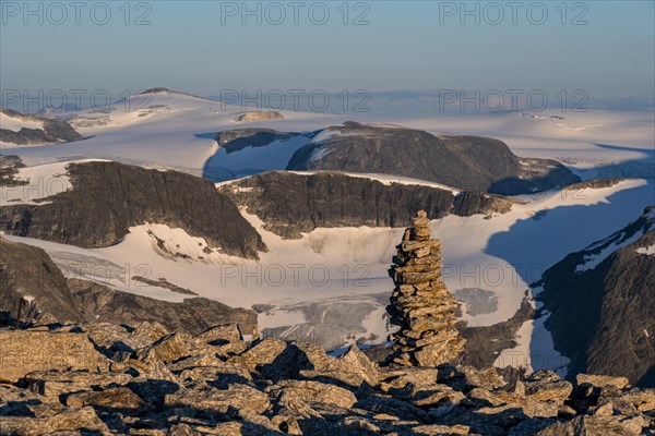 Cairn at the summit of Skala, warm light at sunset, summit and glacier Jostedalsbreen in the background, Loen, Norway, Europe