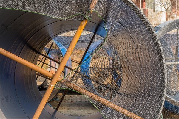 Closeup of large blue sections of steel industrial pipes sitting at construction site