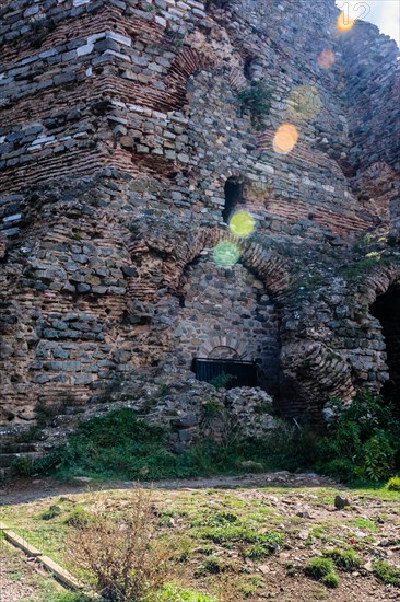 Interior stone and brick wall of castle ruins with lens flares across facade in Istanbul, Tuerkiye