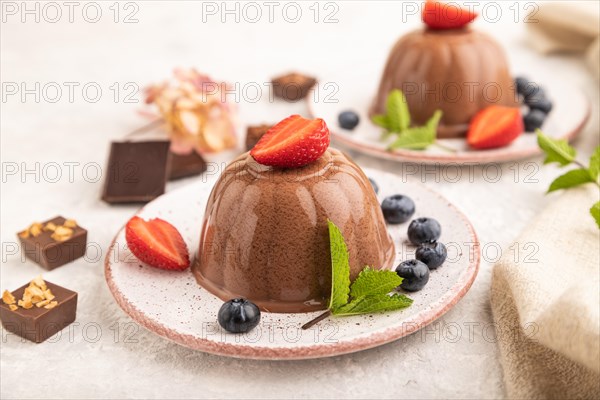 Chocolate jelly with strawberry and blueberry on gray concrete background and linen textile. side view, close up, selective focus