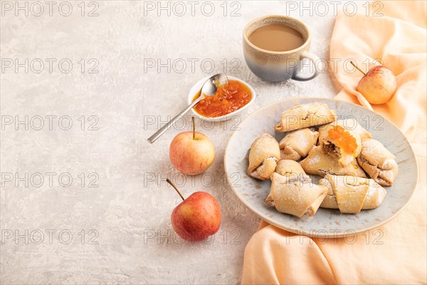 Homemade sweet cookie with apple jam and cup of coffee on gray concrete background and orange linen textile. side view, copy space