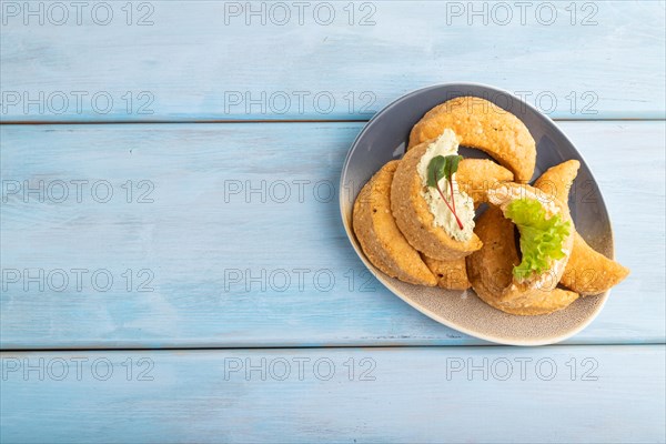Homemade salted crescent-shaped cheese cookies on blue wooden background. top view, flat lay, copy space