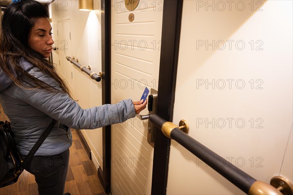 A latin woman is using a key card to unlock a hotel room door