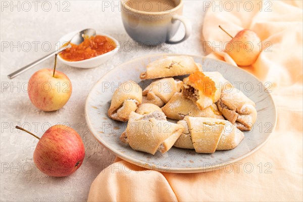 Homemade sweet cookie with apple jam and cup of coffee on gray concrete background and orange linen textile. side view, clsoe up