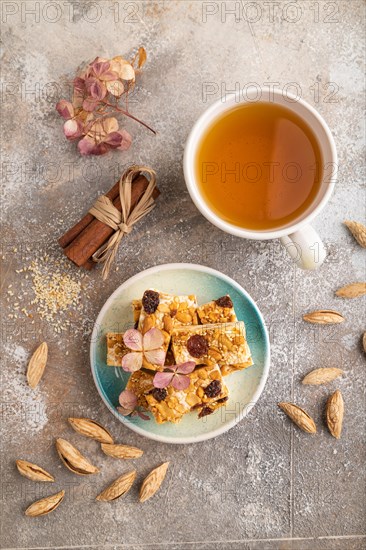 Traditional candy nougat with nuts and sesame with cup of green tea on brown concrete background. top view, flat lay, close up