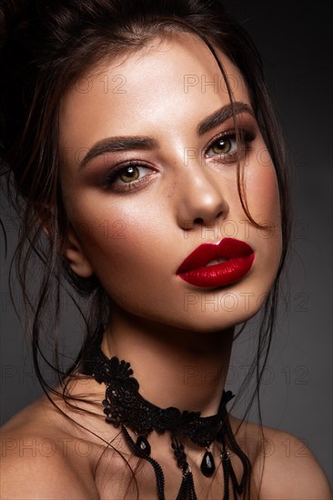 Gorgeous Young Brunette Woman face portrait. Beauty Model Girl with bright eyebrows, perfect make-up, red lips, touching her face. Sexy lady makeup for party