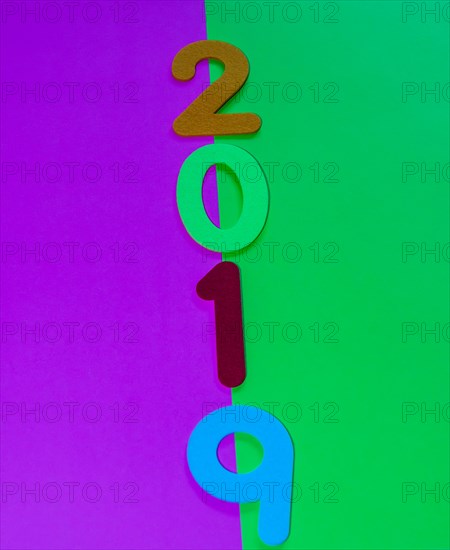 The numbers 2019 made of felt of different colors photographed on green and maroon background