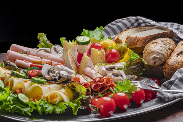 A selection of cheeses and vegan sausages with pastries, vegetables and salad, appetisingly presented on a silver platter