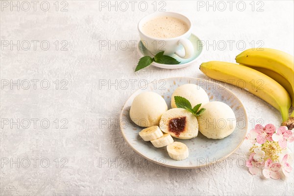 Japanese rice sweet buns mochi filled with jam and cup of coffee on a gray concrete background. side view, copy space