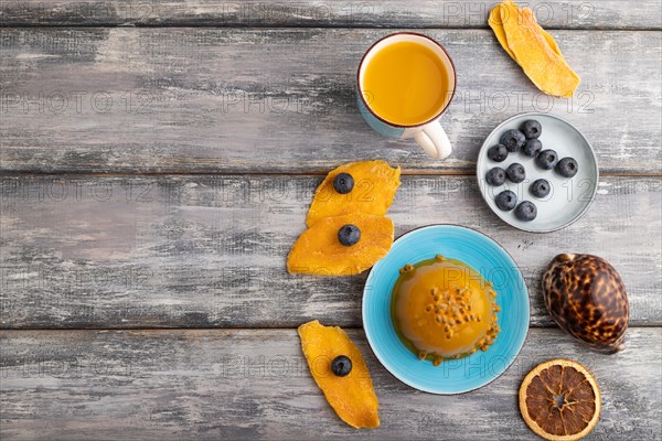 Mango and passion fruit jelly with blueberry on gray wooden background. top view, flat lay, copy space