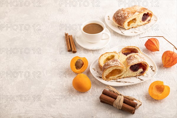 Homemade sweet bun with apricot jam and cup of coffee on gray concrete background. side view, copy space