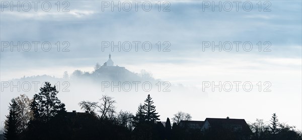 A misty landscape with silhouettes of trees and a chapel on a hill, Wurmlinger Kapelle