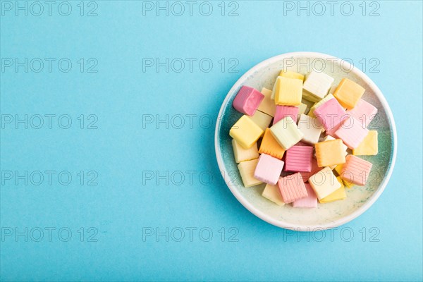 Various fruit jelly chewing candies on plate on blue pastel background. apple, banana, tangerine, top view, flat lay, copy space