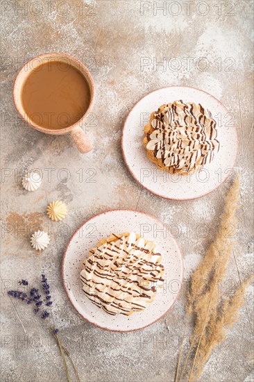 Two tartlets with meringue cream and cup of coffee on brown concrete background. top view, flat lay. Breakfast, morning, concept