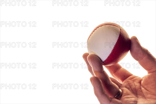 Hand with a juggling ball in front of a white background, studio shot, Germany, Europe