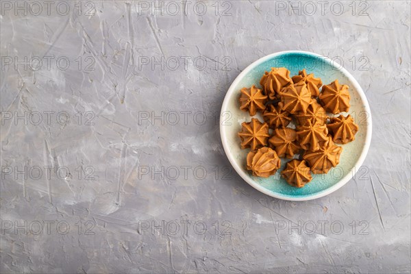 Homemade soft caramel fudge candies on blue plate on gray concrete background. top view, flat lay, copy space