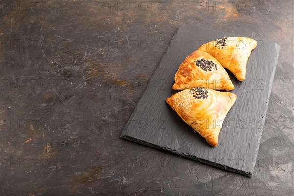Homemade asian pastry samosa on black concrete background. side view, copy space