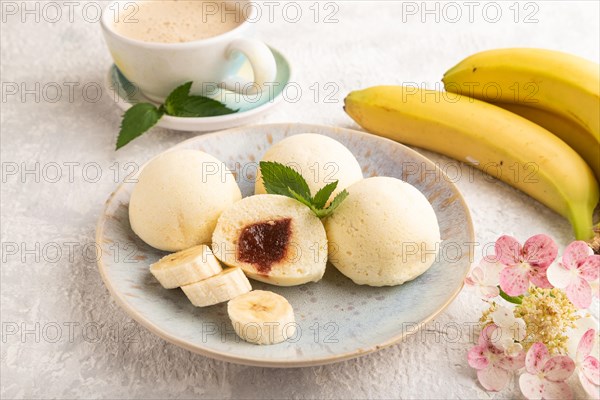 Japanese rice sweet buns mochi filled with jam and cup of coffee on a gray concrete background. side view, close up