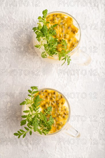 Yogurt with passionfruit and marigold microgreen in glass on gray concrete background. Top view, flat lay, close up