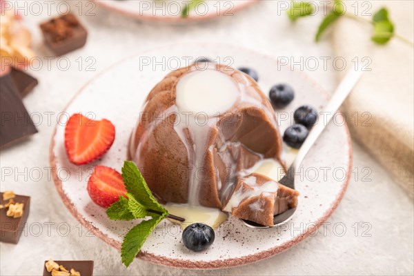 Chocolate jelly with strawberry, blueberry and milk cream sliced with spoon on gray concrete background and linen textile. side view, close up, selective focus