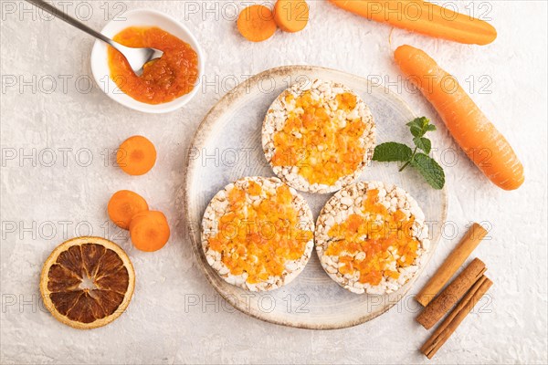 Carrot jam with puffed rice cakes on gray concrete background. Top view, flat lay, close up
