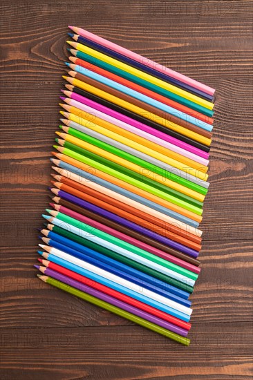 Set of watercolor pencils on brown wooden background. Top view, flat lay, close up