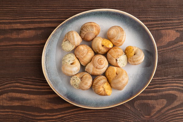 Grape (Burgundy) snails with butter and cheese on brown wooden background. Top view, flat lay