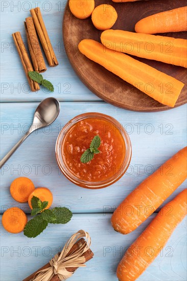 Carrot jam with cinnamon in glass jar on blue wooden background. Top view, flat lay, close up
