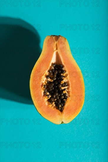 Ripe cut papaya on blue pastel background. Top view, flat lay, close up, hard light. Tropical, healthy food, women health concept, minimalism