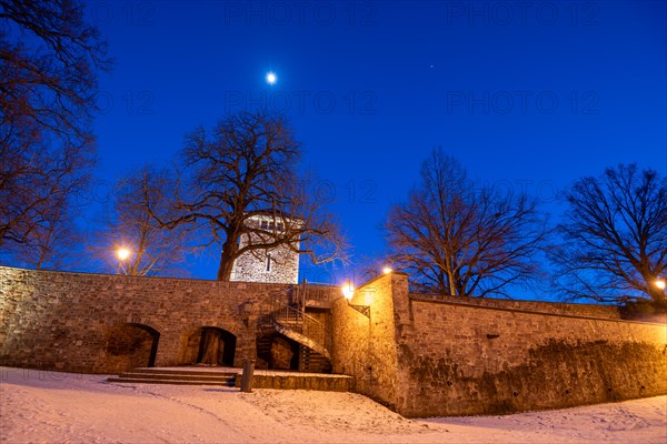 Garden of the Moellenvogtei with historic city wall and defence defence tower under the moon in the evening sky in winter, Magdeburg, Saxony-Anhalt, Germany, Europe