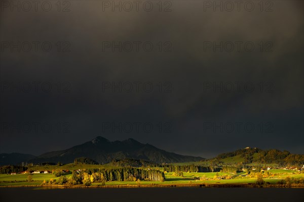 Lake Hopfensee with stormy sky in soft morning light and Allgaeu mountains in the background, Hopfen am See, Ostallgaeu, Swabia, Bavaria, Germany, Europe