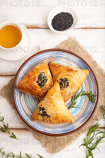 Homemade asian pastry samosa, cup of green tea on white wooden background and linen textile. top view, flat lay, close up