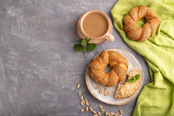 Homemade sweet bun with peanut butter and cup of coffee on a gray concrete background and green linen textile. top view, flat lay, copy space