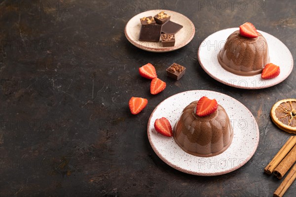 Chocolate jelly with strawberry on black concrete background. side view, copy space