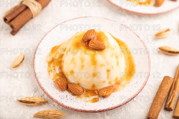 White milk jelly with caramel sauce on gray concrete background. side view, close up, selective focus