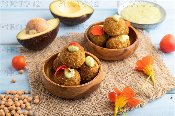 Falafel with guacamole on blue wooden background and linen textile. Side view, close up