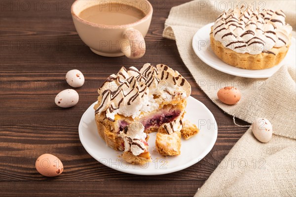 Tartlets with meringue cream and cup of coffee on brown wooden background and linen textile. side view. Breakfast, morning, concept