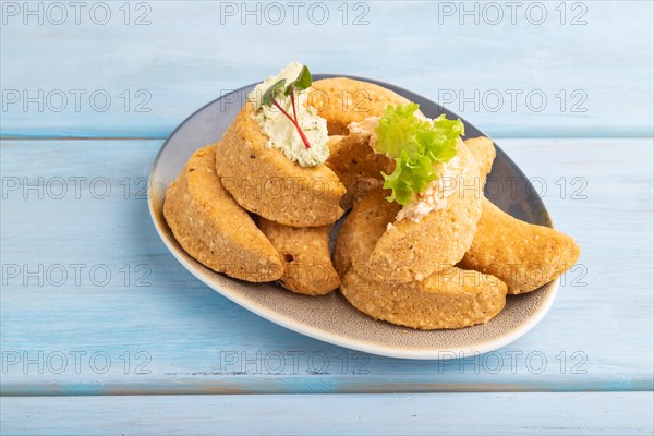 Homemade salted crescent-shaped cheese cookies on blue wooden background. side view, close up