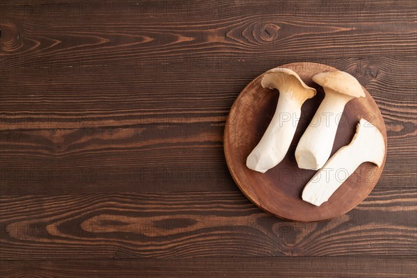 King Oyster mushrooms or Eringi (Pleurotus eryngii) on brown wooden background. Top view, flat lay, copy space