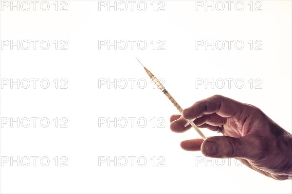 Concept image vaccination, male hand with medical syringe in front of white background, studio shot, Germany, Europe