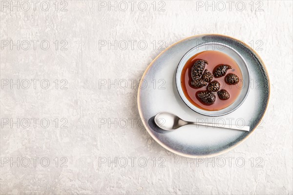 Pine cone jam on ceramic plate on gray concrete background. Top view, flat lay, copy space