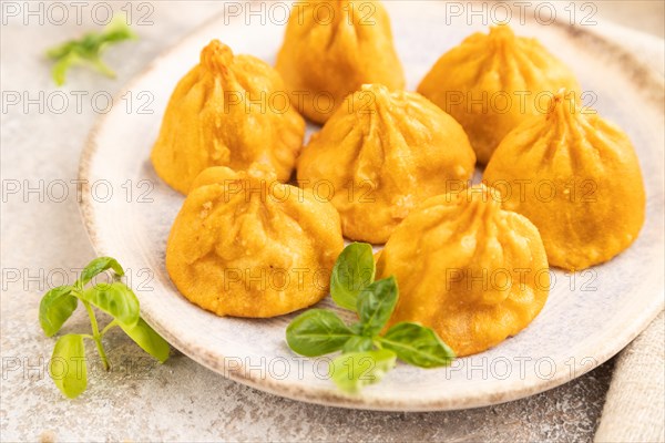 Fried manti dumplings with pepper, basil on gray concrete background and linen textile. Side view, close up, selective focus