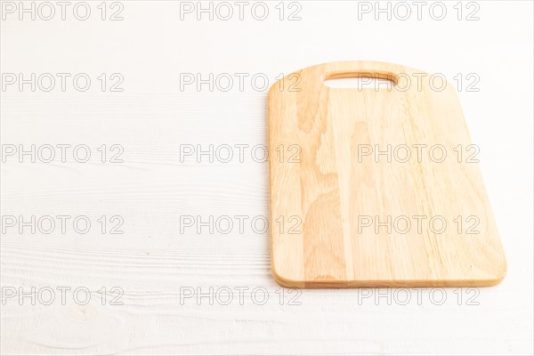 Empty rectangular wooden cutting board on white wooden background. Side view, copy space