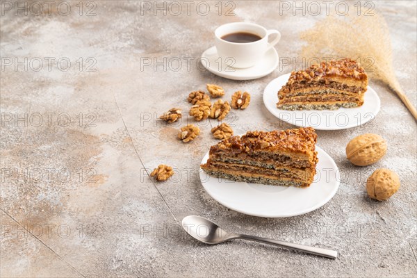 Walnut and hazelnut cake with caramel cream, cup of coffee on brown concrete background. side view, copy space