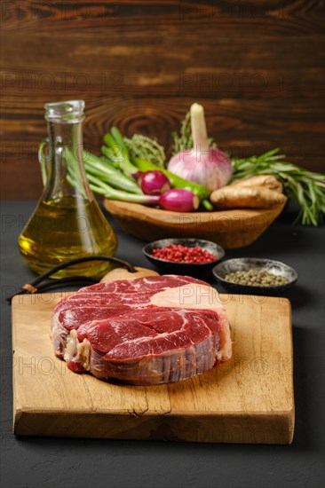 Raw beef ossobuco on chopping board with ingredients for cooking