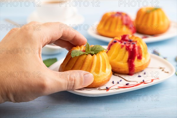 Semolina cheesecake with strawberry jam, lavender, with hand on blue wooden background. side view, close up, selective focus