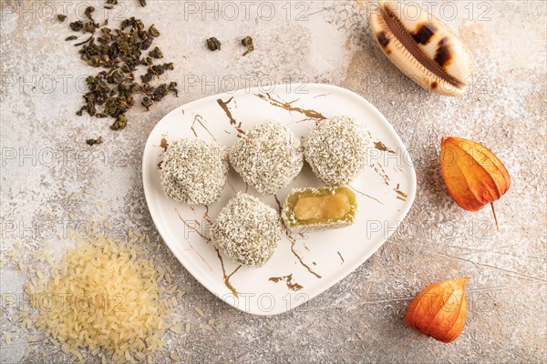 Japanese rice sweet buns mochi filled with pandan jam and cup of green tea on brown concrete background. top view, flat lay, close up