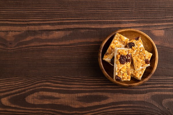 Traditional candy nougat with nuts and sesame on brown wooden background. top view, flat lay, copy space