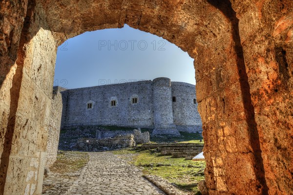 View through an old stone arch onto a sunlit fortress under a clear blue sky, Chlemoutsi, High Medieval Crusader Castle, Kyllini Peninsula, Peloponnese, Greece, Europe