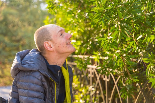 Side view of a happy and smiling disabled man sitting in a wheelchair enjoying nature in a park